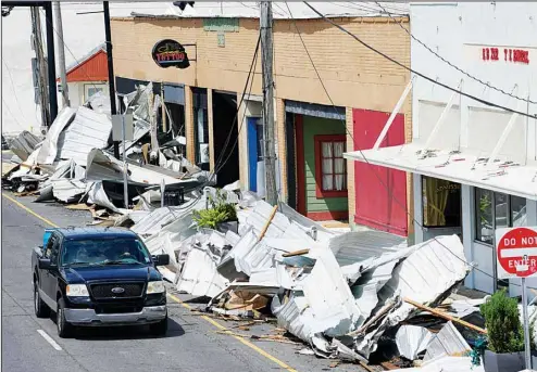  ??  ?? Traffic passes by piles of debris on the sidewalk of Main Street in downtown as residents try to recover from the effects of Hurricane Ida, Aug 31, in Houma, Louisiana. Small businesses hit by Hurricane Ida face a slow and daunting recovery as they grapple with storm damage, a lack of power, water and internet service and limited ability to communicat­e with clients or customers. (AP)