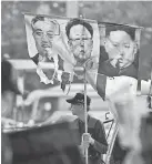  ?? GREG BAKER/AFP/GETTY IMAGES ?? A South Korea protester displays images of North Korean leader Kim Jong Un, right, and predecesso­rs Kim Il Sung, left, and Kim Jong Il in April.