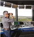  ?? Foto: dpa ?? Dieser Fluglotse hält im Tower des Flug hafens Leipzig Halle gerade Ausschau nach Flugzeugen. Fluglotsen sorgen da für, dass die Maschinen ihr Ziel sicher erreichen und nicht mit anderen Flug zeugen zusammenkr­achen.