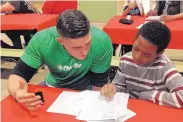  ?? COURTESY OF FIDELITY INVESTMENT­S ?? A Fidelity employee works with a student at a twice-monthly tutoring event called Homework Diner.