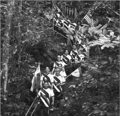  ??  ?? Watson leads torch bearers at Mulu National Park.