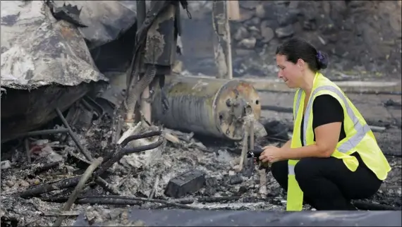  ?? HOWARD LIPIN/THE SAN DIEGO UNION-TRIBUNE VIA AP ?? A woman looks at the charred remains of her mobile home after she has lived for more than eight years, in Alpine, on Saturday. it was destroyed by a wildfire in the Alpine Oaks Estates where