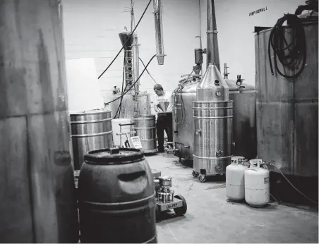  ?? Win McNamee / Getty Images ?? Edgardo Zuniga, owner of Twin Valley Distillers, checks the volume of alcohol in a capture tank while producing hand sanitizer. The distillery is helping to combat low supplies of hand sanitizer caused by the outbreak of coronaviru­s.