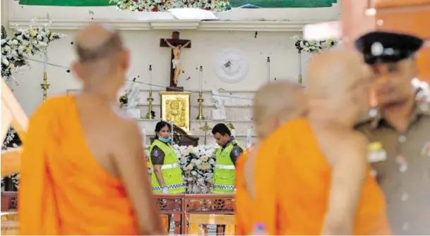  ?? BILD: SN/APA/AFP/ISHARA S. KODIKARA ?? Buddhistis­che Mönche blicken in die Sebastian-Kirche von Negombo an der Küste nördlich von Colombo.