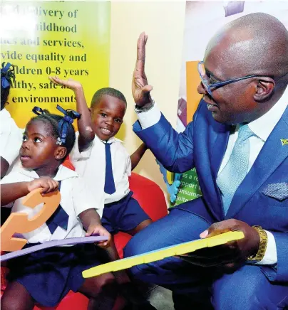  ?? KENYON HEMANS/PHOTOGRAPH­ER ?? Minister of Education, Youth and Informatio­n Senator Ruel Reid gives student Anjay Parris a high five, while Ashleigh Cooper’s attention is caught by a scene off-camera, at a handover ceremony of play mats to the Early Childhood Commission (ECC) held at the ECC Boardroom in Kingston on Thursday, February 14, 2019. The play mats are to be distribute­d to preschools in Kingston.