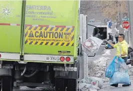  ?? CLIFFORD SKARSTEDT EXAMINER ?? A worker from Emterra Environmen­tal company empties blue boxes along Bethune
Street on Tuesday.