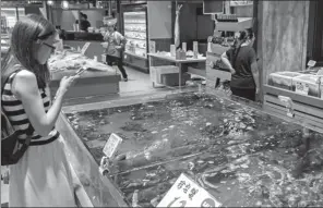  ?? WANG GANG / FOR CHINA DAILY ?? A customer chooses seafood at a supermarke­t of Bailian Group in Shanghai. The company is setting up a commodity trading platform targeting sales of a trillion yuan.