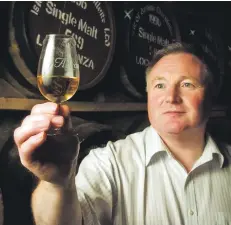  ??  ?? James inspects a glass of Arran whisky at the distillery.