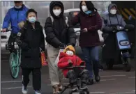  ?? (AP/Ng Han Guan) ?? A family walks across the street Friday in Beijing.