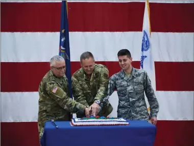  ?? U.S. ARMY NATIONAL GUARD PHOTO BY RYAN CAMBELL ?? Major General Timothy LaBarge(center) the Commander of the New York Air National Guard joins Army National Guard Master Sgt. Roger Townsend, age 59(left); and Air National Guard Airman 1st Class Caleb Lapinel, age 21( right) in cutting the National Guard Birthday Cake at a ceremony marking the 383rd birthday of the National Guard held on Friday, Dec. 13at New York National Guard Headquarte­rs in Latham, N.Y. The cake cutters traditiona­lly include an older service member, symbolizin­g the history of the National Guard, an a young serice member, who represents the future of the Guard.