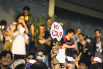  ?? Associated Press ?? A protester raises a placard critical of Thailand’s military leadership during a demonstrat­ion in Bangkok. The military has repeatedly postponed plans to conduct elections.