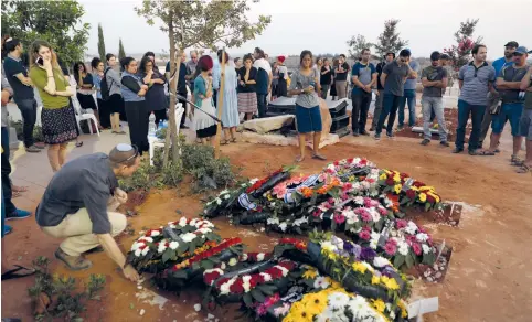  ??  ?? MOURNERS ATTEND the funerals of Chaya, Elad and Yossi Salomon, whom a terrorist killed in Neveh Tzuf (Halamish) on July 14.