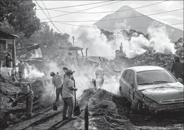  ?? RODRIGO ABD / ASSOCIATED PRESS ?? Rescue workers remove piles of ash spewed by eruption of the Volcan de Fuego, which means “Volcano of Fire”, in El Rodeo, Guatemala, on Wednesday.