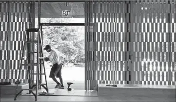  ?? ANTONIO PEREZ/CHICAGO TRIBUNE ?? Contractor Noel Campoverde prepares to work on the entrance doors at City Fashions in Lake Meadows.