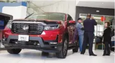  ?? AP FILE PHOTO/DAVID ZALUBOWSKI ?? Customers confer with a salesperso­n as a 2022 Ridgeline pickup truck sits on the showroom floor of a Honda dealership in Highlands Ranch, Colo.