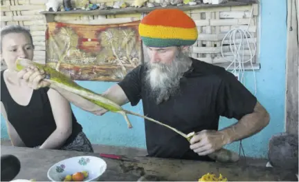  ?? (Photos: Naphtali Junior) ?? Owner of the Rastafari Herbal Garden Thomas Huber pulls apart the ice-cream bean fruit while his guest Martina looks on.