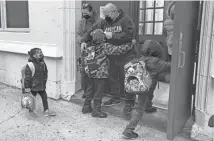  ?? JENNIFER PELTZ/AP ?? John Marro, dean of students at P.S. 347 in New York, takes students’ temperatur­es as they arrive at school Monday. New York City schools reopened after the holiday break despite a surge in coronaviru­s infections.