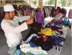  ??  ?? MOHD Nazir menyusun pakaian terpakai untuk dijual.