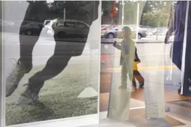  ?? Lea Suzuki / The Chronicle ?? People pass a window display at Macy’s Stonestown store, which was sold to the mall owner a year ago.