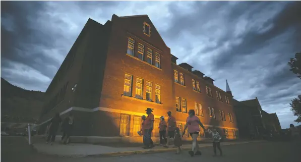  ?? PHOTOS: DARRYL DYCK/THE CANADIAN PRESS ?? People are silhouette­d as they walk past the former Kamloops Indian Residentia­l School after gathering to honour the 215 children whose remains were discovered last year buried in unmarked graves near the facility.