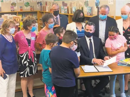  ?? Emma Talley / The Chronicle ?? Gov. Gavin Newsom signs California’s new budget with help from masked students at Shearer Elementary School in Napa.