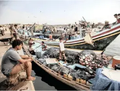  ?? AP ?? A FISHERMAN sits on the pier near boats at the main fishing port, in Hodeida, Yemen. |