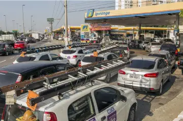  ??  ?? Vehicles sit in line to refuel on Thursday in Sao Paulo, Brazil, where a truckers strike over rising fuel costs has halted deliveries and caused a shortage of goods and services throughout the country.— WP-Bloomberg photo by Rodrigo Capote