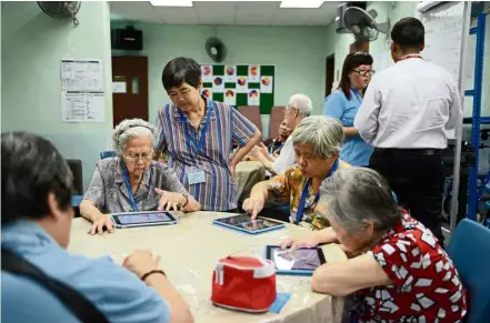  ?? — SPH ?? Elderly people can be seen playing mobile games on tablets in this filepic. It has been found that those with a genetic risk of developing Alzheimer’s disease play a certain mobile game differentl­y from others.