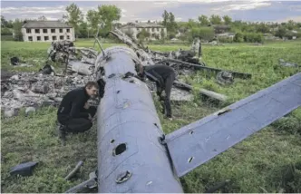  ?? BERNAT ARMANGUE/AP ?? Oleksiy Polyakov (right) and Roman Voitko check the remains of a destroyed Russian helicopter in a field in the village of Malaya Rohan, Kharkiv region, Ukraine, Monday.