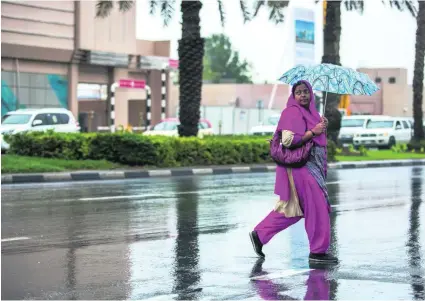  ?? Victor Besa for The National ?? Many residents, such as this Dubai shopper, have become used to carrying an umbrella as the rain continues.