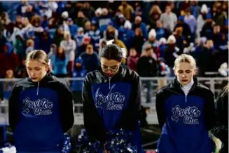  ?? CRAIG F. WALKER/GLOBE STAFF ?? Lewiston High School cheerleade­rs bowed their heads during a moment of silence before the football game against Edward Little on Wednesday.