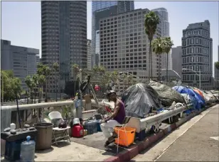  ?? RICHARD VOGEL — THE ASSOCIATED PRESS ?? A homeless man sits at his street side tent along the Interstate 110Freeway along downtown L.A.'s skyline in 2018. Tent encampment­s are the central issue in a case heading to the Supreme Court.