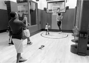  ?? DEWAYNE BEVIL/ORLANDO SENTINEL ?? NBA Experience visitors take turns dunking on an adjustable goal and perform other basketball-driven tasks at the Disney Springs attraction.