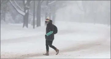  ?? The Associated Press ?? HIGH AND HEAVY: A pedestrian makes her way across empty Speer Blvd. as a storm packing snow and high winds sweeps in over the region Tuesday, in Denver.