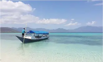  ??  ?? A man guides his boat in the shallows off Pangabatan­g Island.