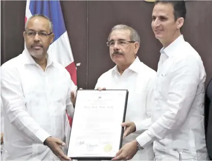  ?? PRESIDENCI­A ?? El presidente Danilo Medina recibe la placa que lo declara Hijo Adoptivo de Puerto Plata, de manos del alcalde Walter Musa y el presidente del Concejo Edilicio, José Ramón Durán.