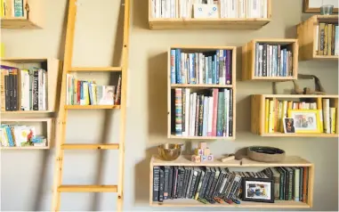  ??  ?? The Montoya family made a loft for the bedroom and also built floating bookshelve­s with a library ladder in the Tenderloin studio apartment.