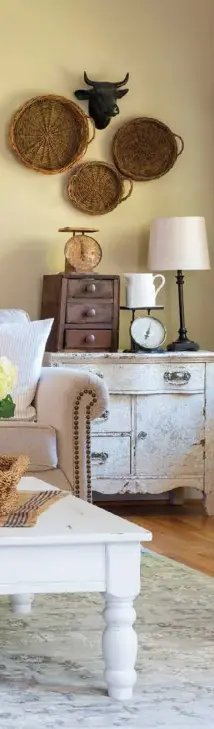  ??  ?? An old gate is a distinctiv­e statement piece on Amy Grassinger’s family room wall. Placing a long sign above and a wreath directly on the gate creates more depth. Baskets, a cow-head wall decoration and simple artwork bring added interest. Seating piled with ticking and grain-sack pillows makes the room comfy when the family gathers there to watch television.