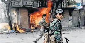  ?? Picture: AFP/Bulent Kilic ?? TAKING CONTROL: Turkish-backed Syrian rebels walk past a burning shop in the city of Afrin in northern Syria