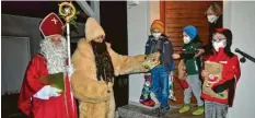  ?? Foto: Langhans ?? Nikolaus und Knecht Ruprecht zu Besuch bei der Familie Jenuwein. Ihre Gaben erhalten Theo, Valentin und Vitus (von links) diesmal vor der Haustüre.