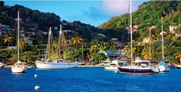  ??  ?? LAID-BACK: Vibrant beachside villas, above, on Little Cayman and, left, the pretty harbour at Port Elizabeth, capital of Bequia