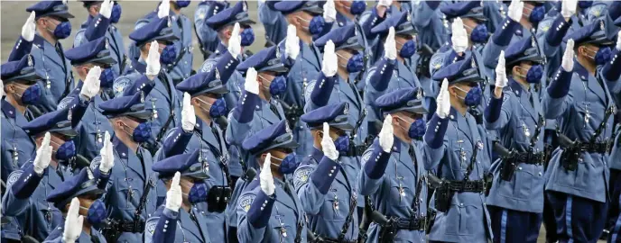  ?? STuART cAHiLL pHOTOs / HeRALd sTAFF ?? SPECIAL DAY: Recruits take the oath of office to become state troopers Thursday in Worcester. Below, new trooper Mark Langley holds his son, Killain, outside the DCU Center. At bottom, retired trooper Paula Loud pins the badge on her son, Steven, during the ceremony.