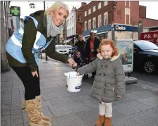  ??  ?? Jessie Kelly Kieran puts a donation in the bucket held by Tanya McCabe at the annual sleepout for Drogheda Homeless Aid last year. Every cent counts on 2017 too.