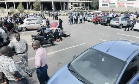  ?? PICTURE: DUMISANI SIBEKO ?? AWAITING CLEARANCE: Employees and customers at Clearwater Mall in Roodepoort wait in the parking area after the mall was evacuated yesterday following a bomb scare. They were allowed back after police explosives experts and dogs had searched the centre.