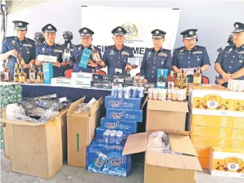  ?? ?? Mohd Nasir (center) and Customs officers showing some of the seized alcohol and cigarettes.