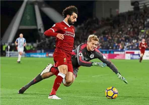  ?? — Reuters ?? No, you don’t: Huddersfie­ld goalkeeper Jonas Lossl (right) trying to stop Liverpool striker Mohamed Salah from scoring during their English Premier League match at the John Smith’s Stadium on Tuesday.