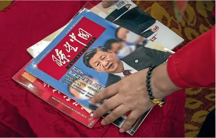  ?? AP ?? A Chinese journalist picks up a magazine with President Xi Jinping on the cover at this week’s Chinese Communist Party 20th national congress in Beijing. Chinese foreign policy is being driven by what Xi sees as mounting security risks – but the expansion of its internatio­nal security presence and aggressive style of diplomacy is putting China on a collision course with other nations.