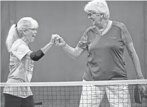  ??  ?? Sheila Brandenbur­g, left, and Ginny Whitley celebrate after scoring a point while playing pickleball at the Singleton Community Center on Wednesday morning. JIM WEBER/THE COMMERCIAL APPEAL