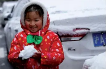  ?? XINHUA ?? A girl plays with snow in Shanghai on Thursday after a snow fall, a relatively rare phenomenon for the eastern Chinese city.