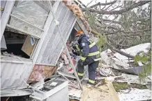  ?? — AP ?? ALBANY: A rescue worker enters a hole in the back of a mobile home in Big Pine Estates that was damaged by a tornado.